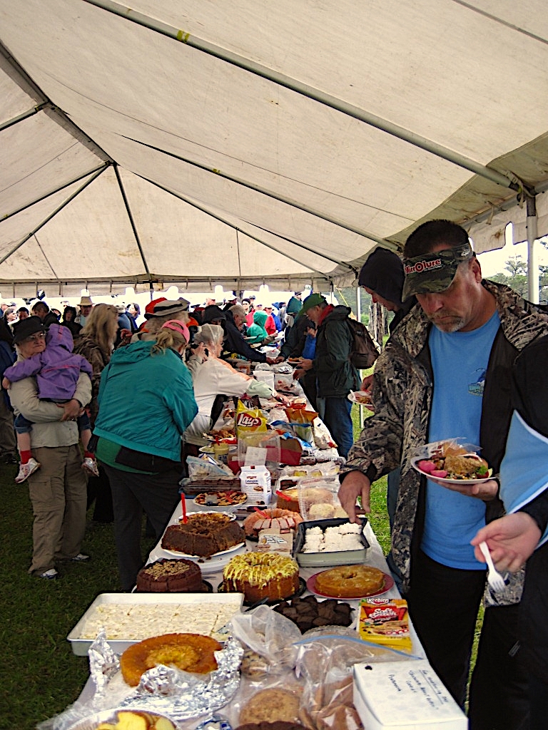 image: People gather around tables of food.